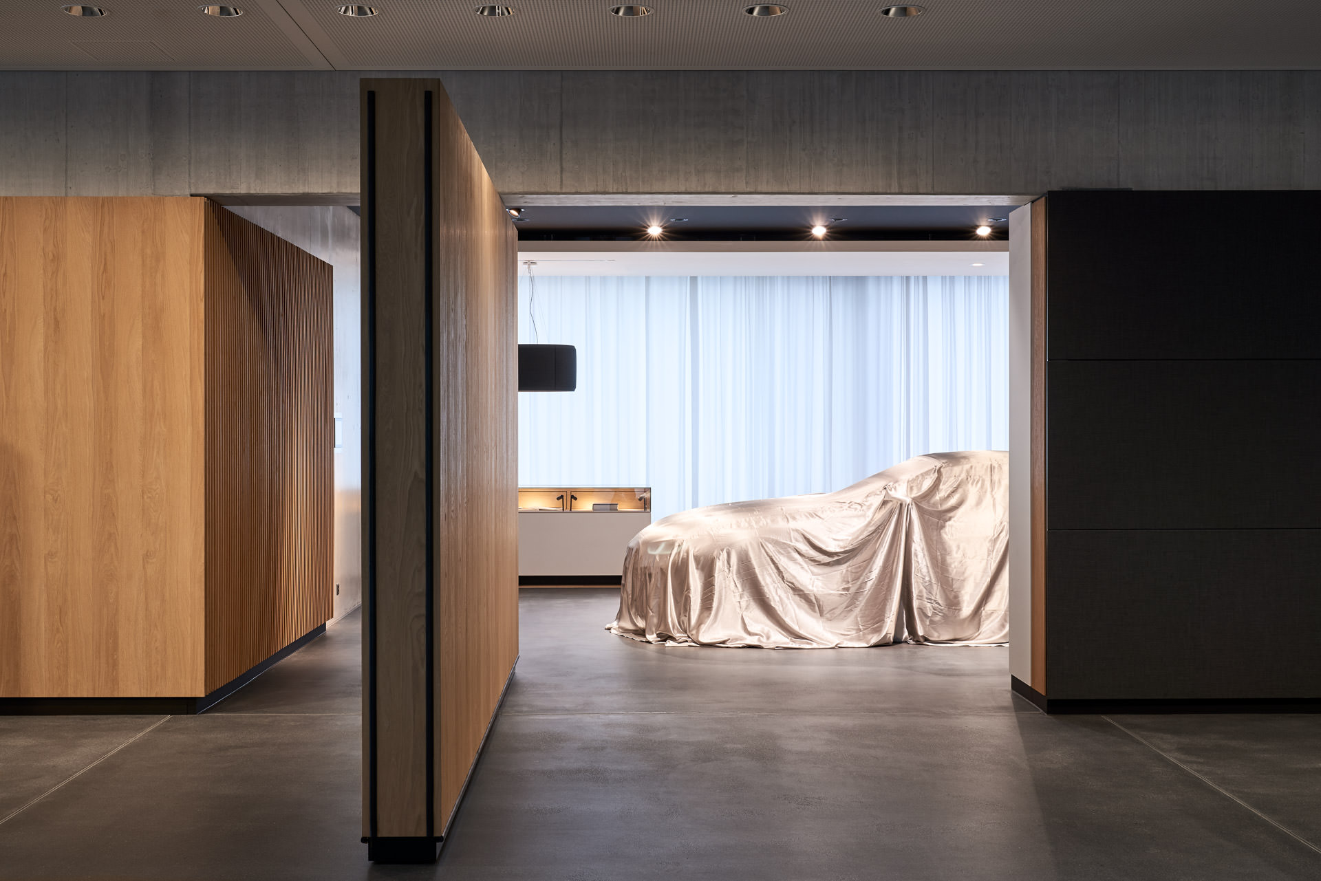 Interieur-Fotos bei BMW. Fahrzeug unter Abdeckung in luxuriösem Ambiente.