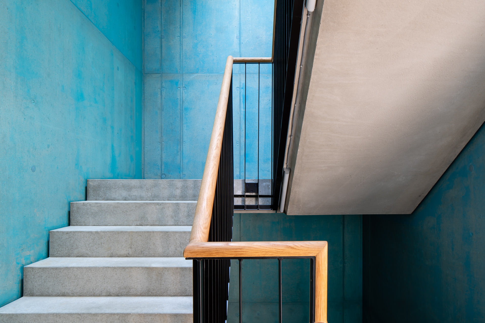 Staircase, blue, concrete walls, wooden grip - Photographer Zurich