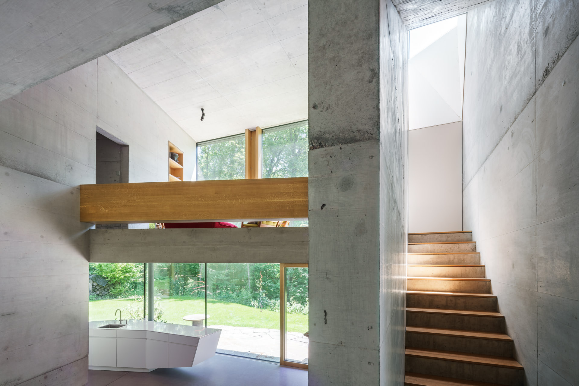 Open living, dining and staircase rooms with concrete walls in casa forest by Interior & Architecture Photographer.