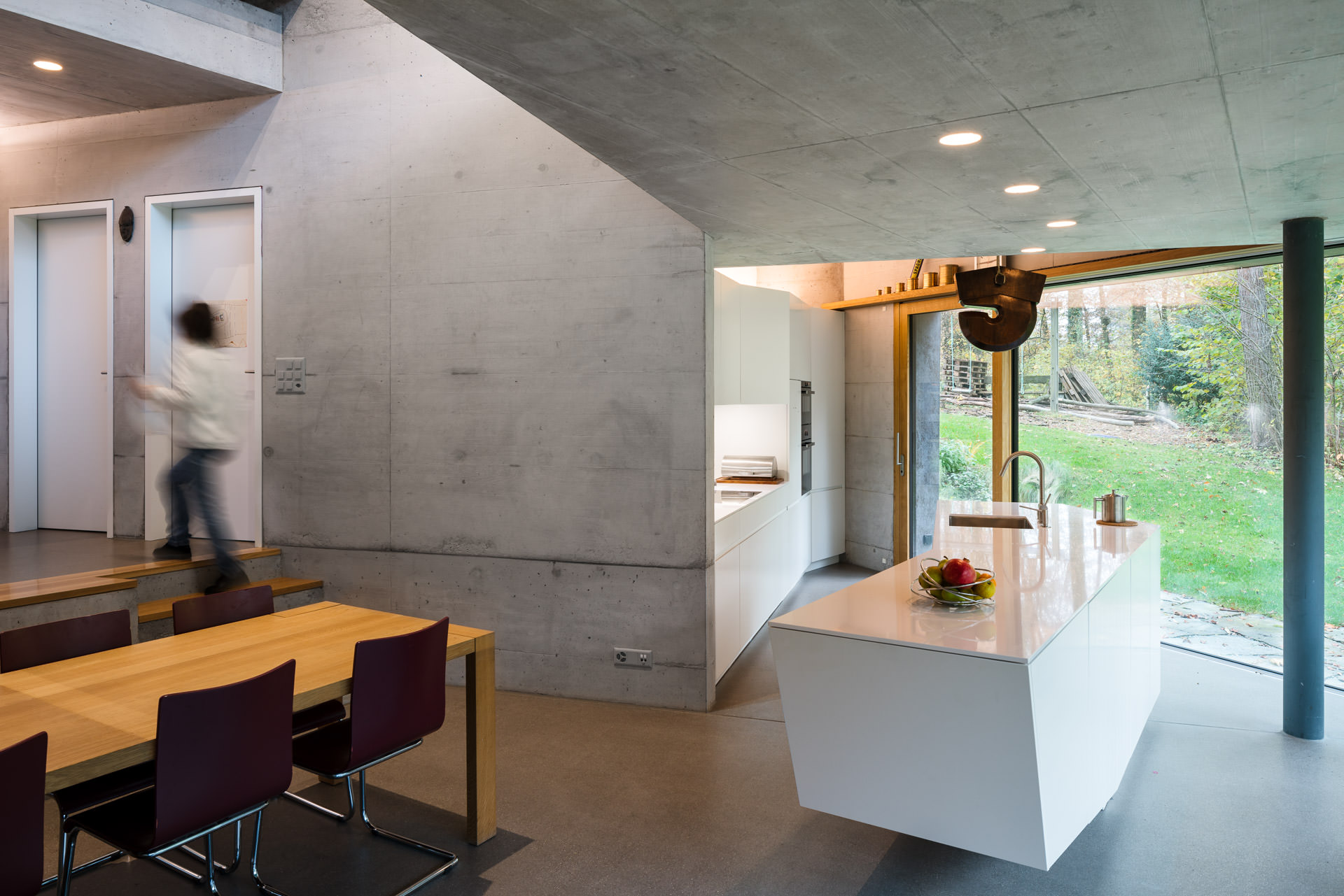 Modern kitchen in Casa Forest by Daluz Gonzalez Architects. Moving person in the image.