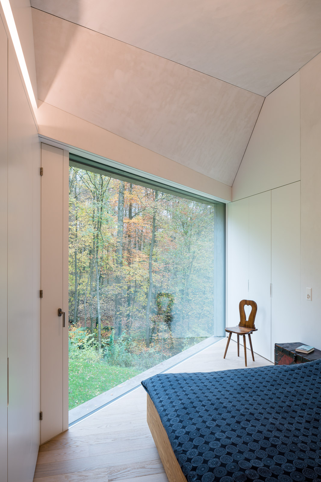 Moderne Architekturfotografie Innenraum Interieur: Schlafzimmer mit Ausblick in den Herbstwald