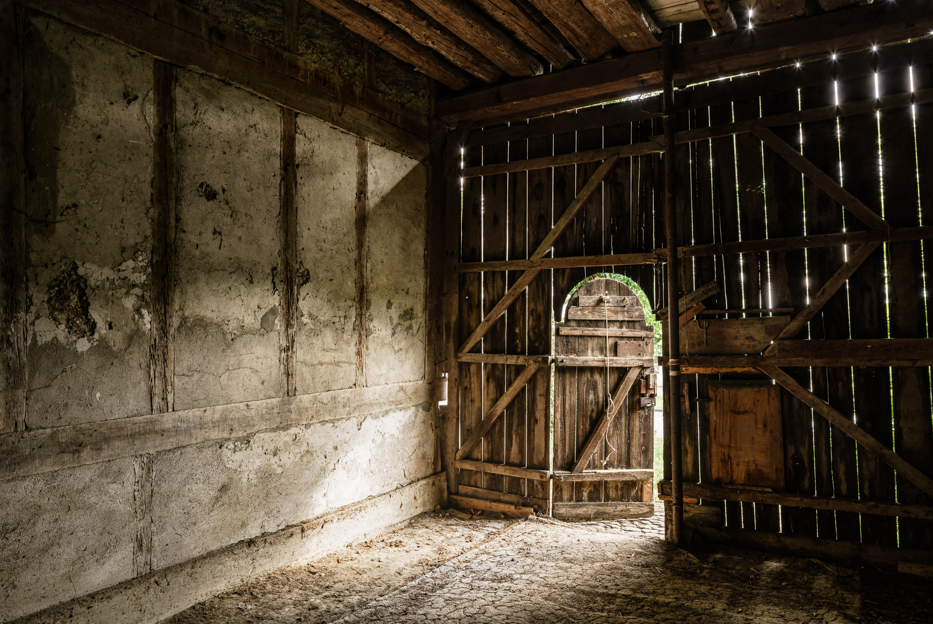 Scheunentür Innenseite, leicht geöffnet, Zugang zum Stall aus altem Holz, teilweise unter Denkmalschutz.