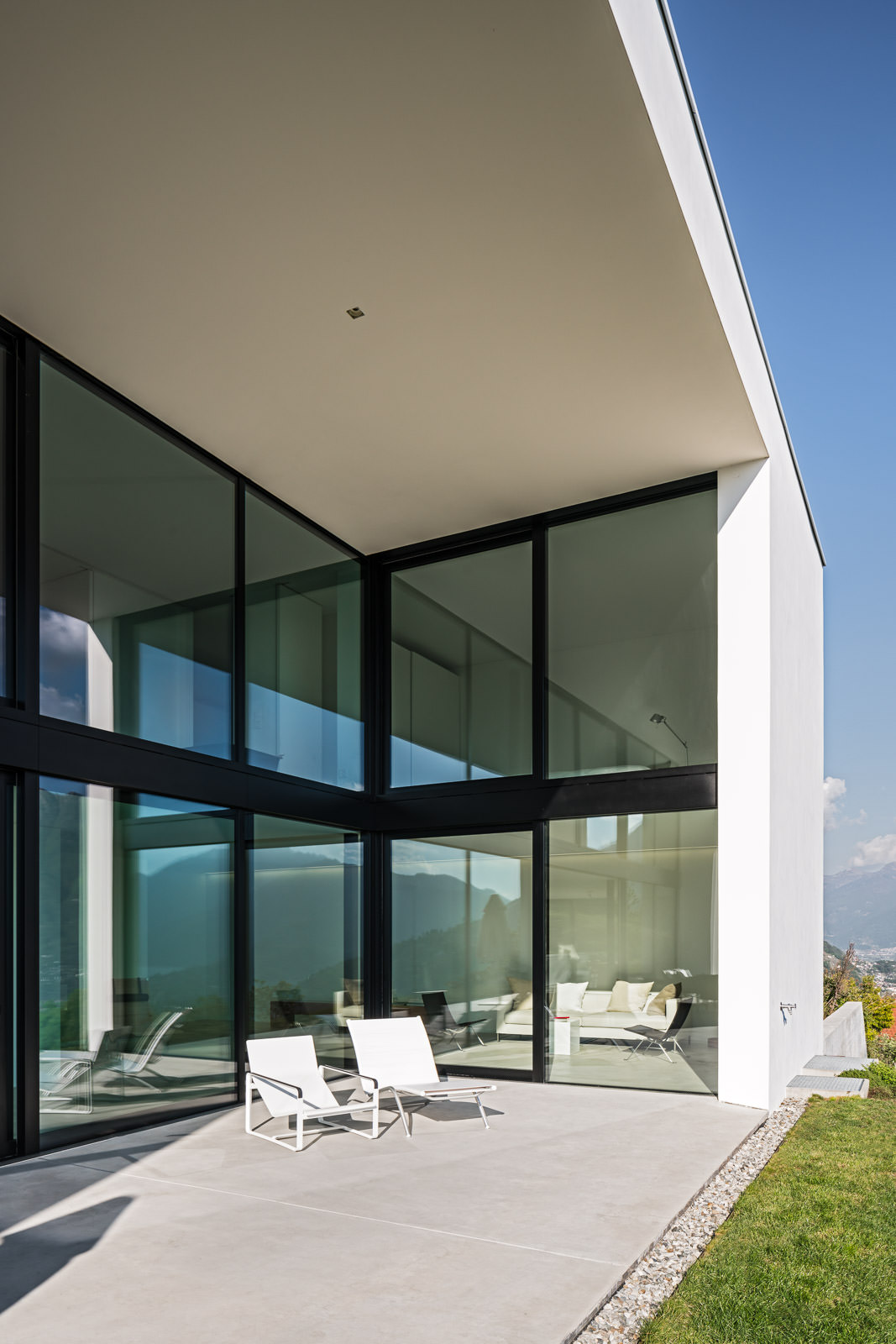 Impressive sunny side terrace with a two floor window front and two lounge chairs. Design Daluz, Gonzalez & Cajos Architects