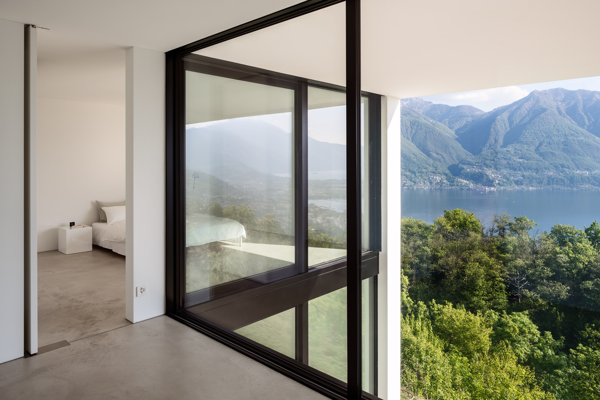 Room high windows opening towards a stunning lake and mountain view. Interior Architectural Photography Switzerland - Architectural Photographer