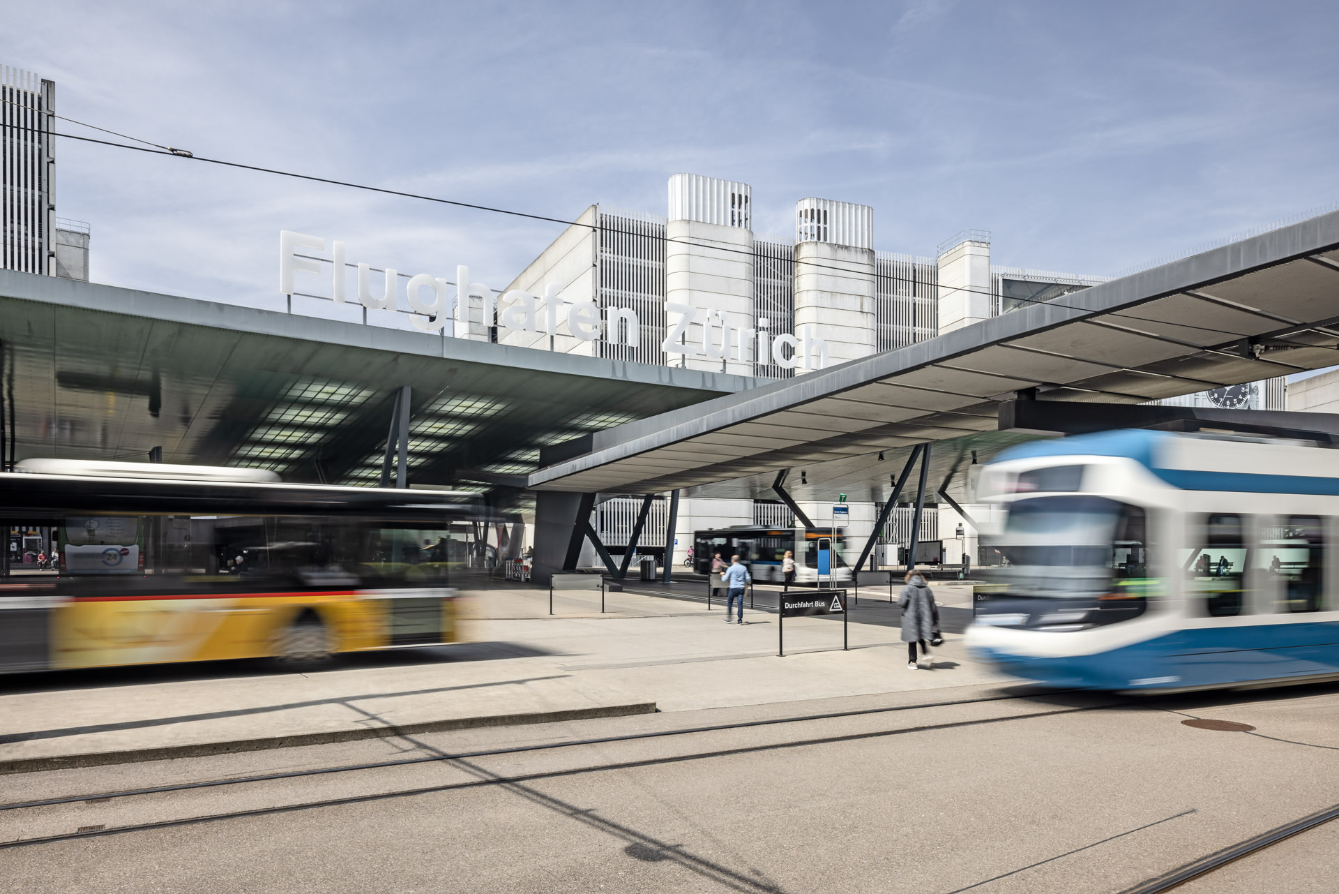 Tram und Bus in Bewegung am Öffentlicher Verkehr Bahnhof des Flughafen Zürich vor Parkhäusern